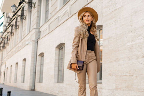 a woman walking down a street in a pale brown leather jacket and pants
