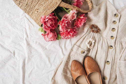 a linen summer dress in a neutral color, shown with shoes and a basket of flowers