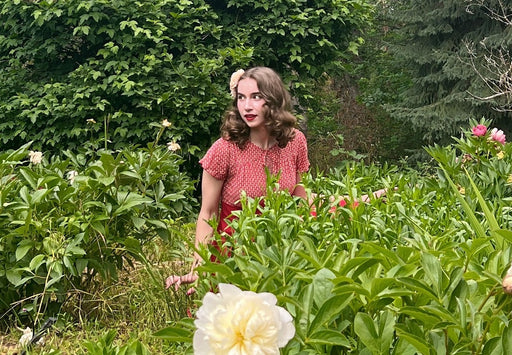 Marley in a garden of flowers wearing a 1940’s red dress