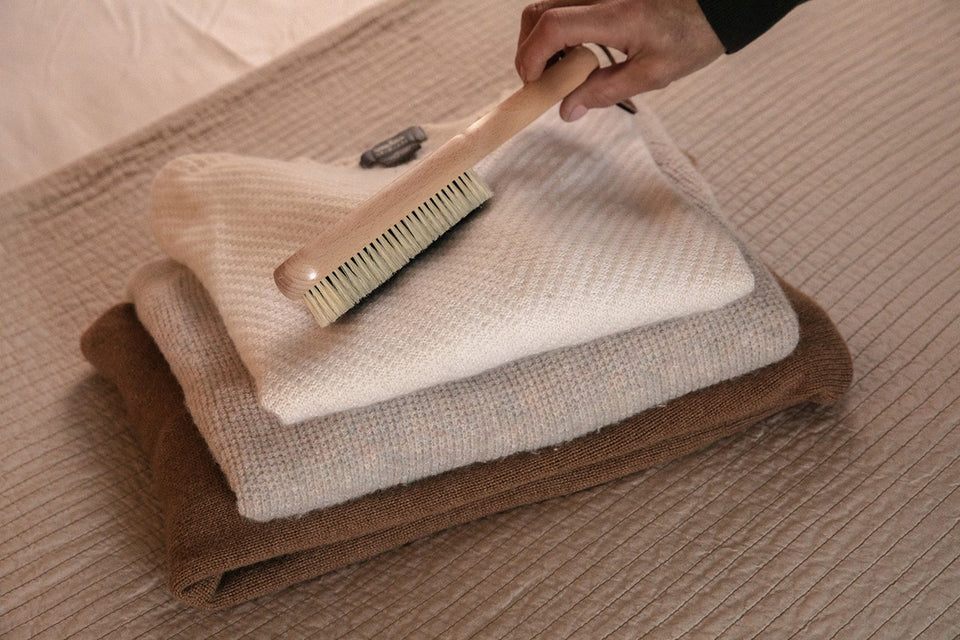 a clothes brush on top of a pile of cashmere sweaters