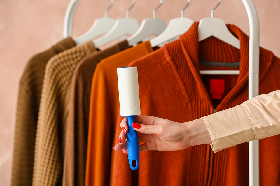 a selection of woolen sweaters on a clothes rail with a lint roller