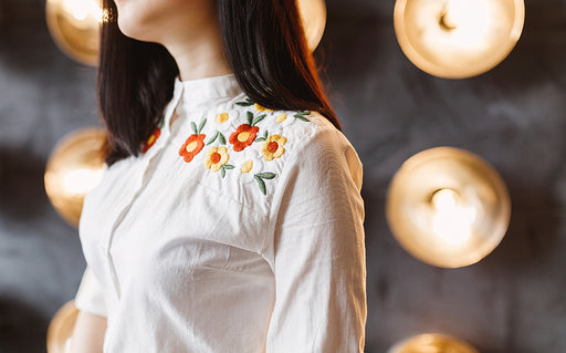 a white shirt with floral embroidery detail on the shoulders