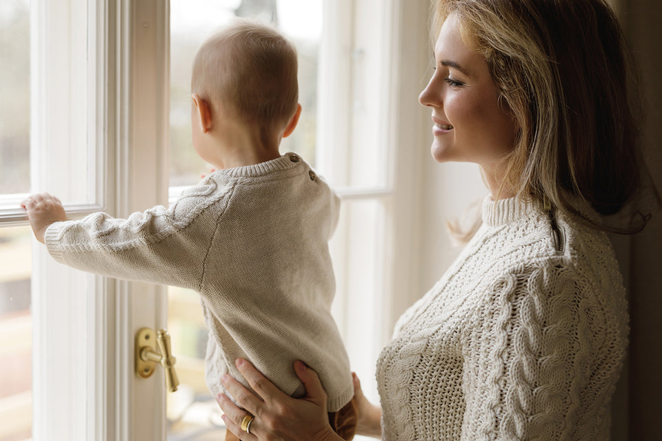 a woman holding her baby, both dressed in cream woolen sweaters
