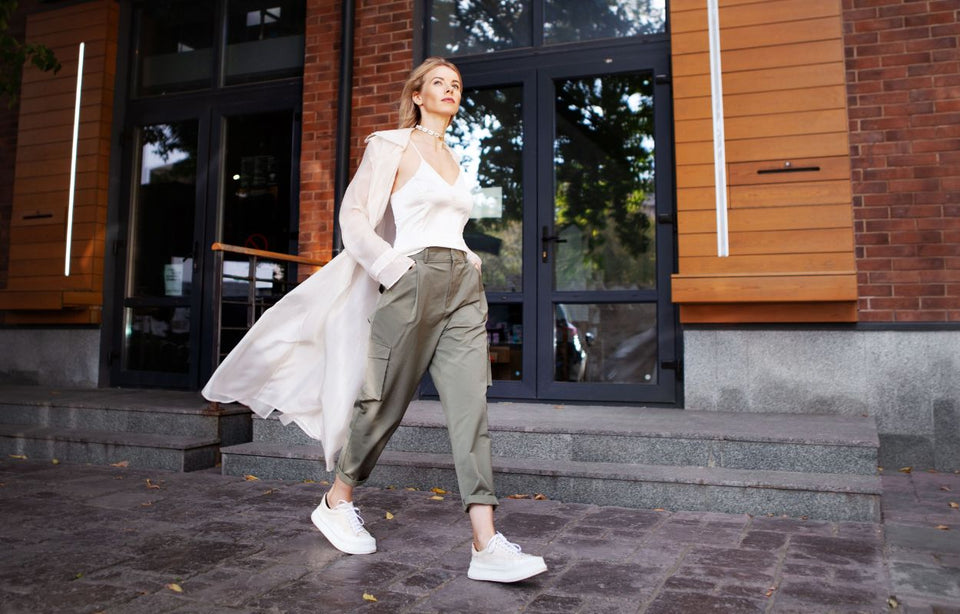 a woman in her thirties wearing a silky coat with a camisole top khaki cargo pants and sneakers
