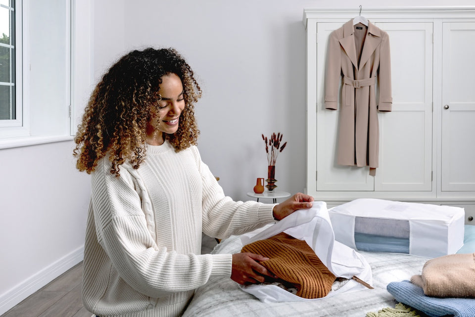 a woman taking her brown sweater out of a Hayden Hill organic cotton breathable storage bag