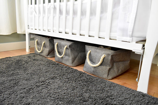 canvas storage bags with handles stored under a crib