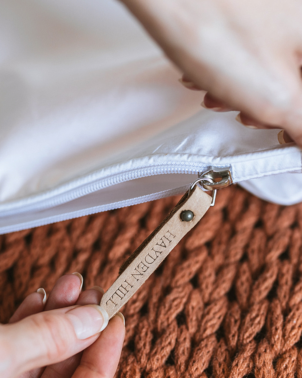 a close up of a hand pulling the leather zipper pull on a storage bag
