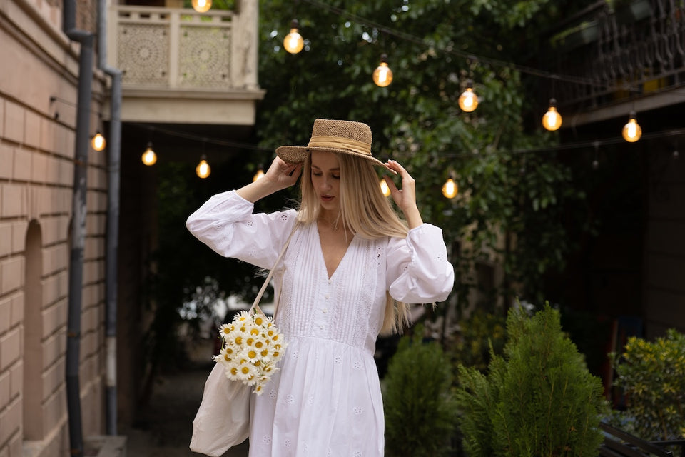 a woman wearing a white cotton dress and a straw hat