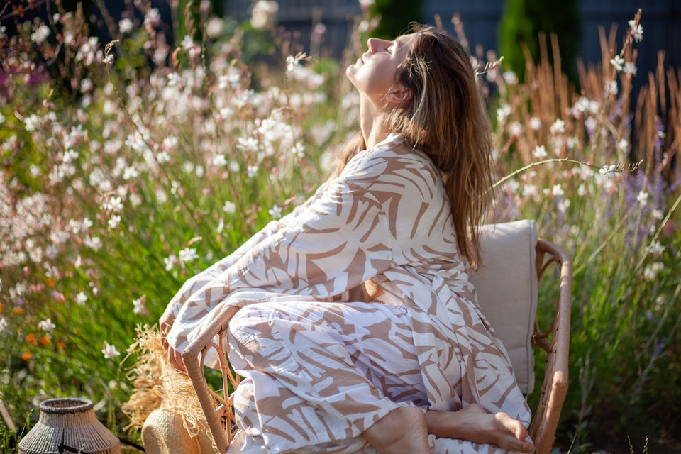 a woman in a summer patterned kimono sitting on a chair in her garden,enjoying the sunshine
