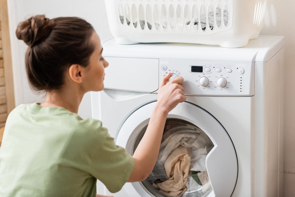 a woman turning the dial on her washing machine