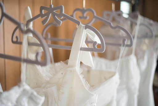 wedding dresses hanging on slim gray velvet hangers