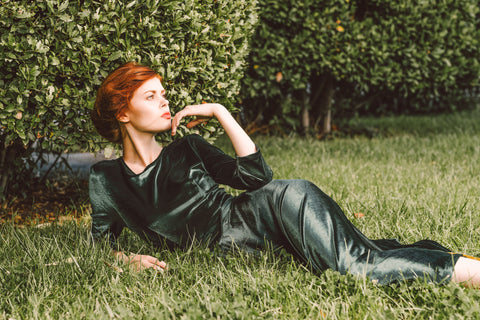 a glamorous woman wearing a green velvet dress lying in green grass