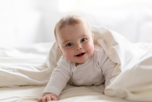a smiling baby in bed wearing hypoallergenic clothing