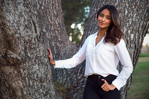 a beautiful stylish woman pictured in front of a large tree trunk