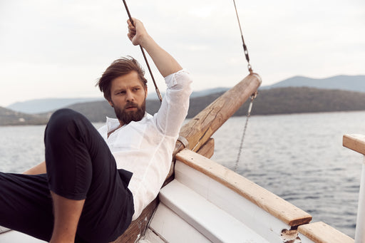 handsome man relaxing on a boat, dressed in casual linen shirt and pants