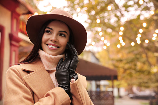 a stylish woman wearing a camel coat, roll-neck sweater, leather gloves and hat