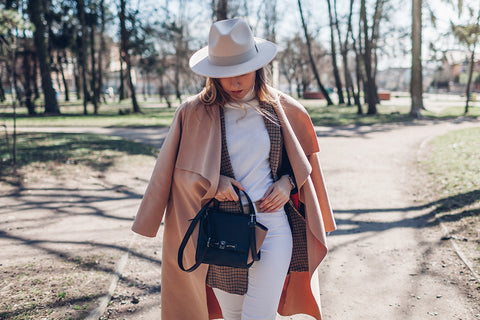 a stylish woman wearing a white outfit and hat, layered with a check jacket and coat