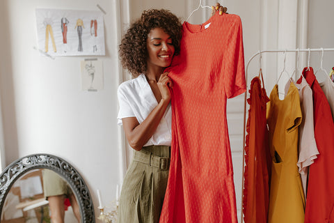 a stylish woman holding up a coral colored dress