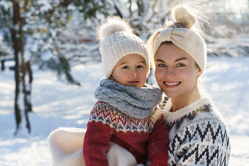 a mother and child staging in the snow, wrapped up in warm woollen winter sweaters