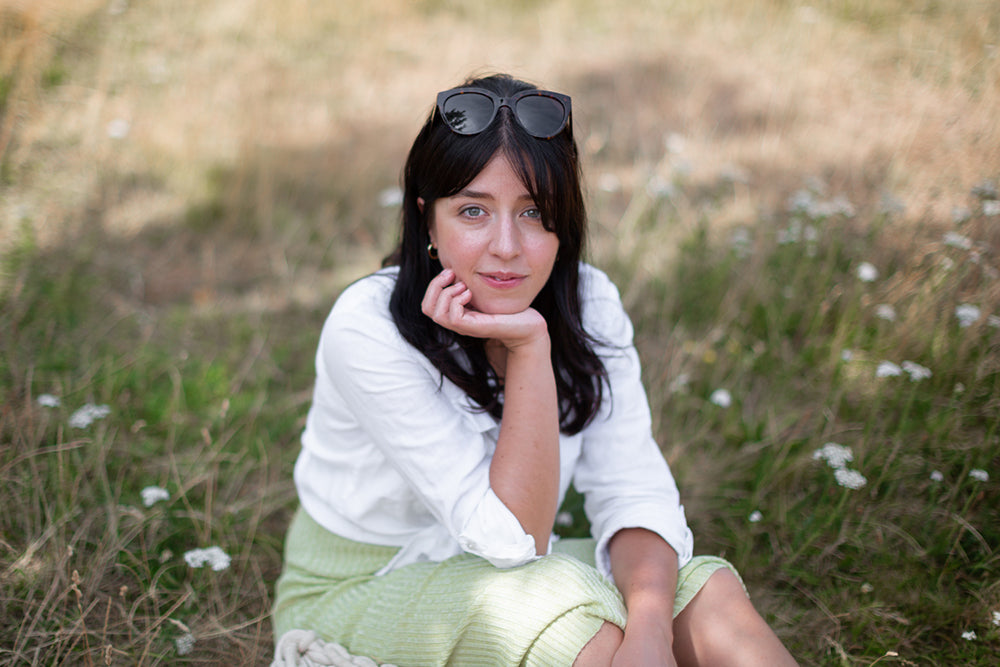 Besma sitting in a field, in summer clothing