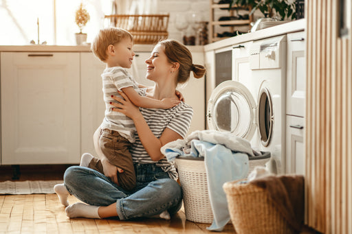 a woman and child sitting by the washing machine