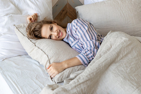 a smiling woman in striped nightshirt relaxing in bed
