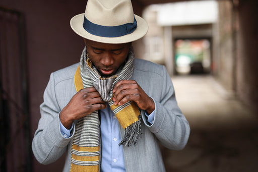 a stylish man wearing a panama hat, scarf and jacket