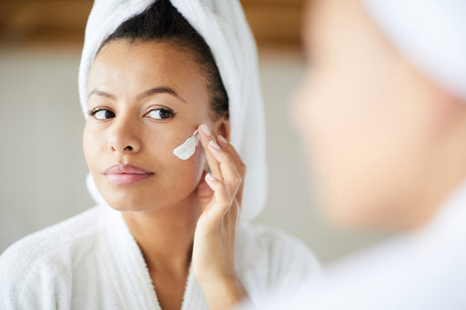 a woman applying a facial product to her beautiful makeup-free skin