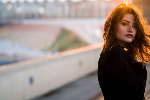 a woman dressed in black with the sun setting behind her