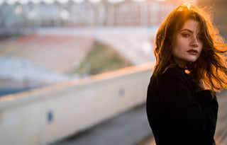 a woman dressed in black with the sun setting behind her