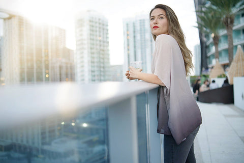 a woman having drinks on a rooftop terrace at dusk
