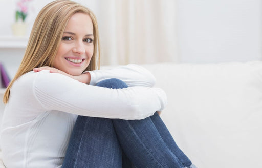 a woman sitting on her couch in a pair of blue jeans