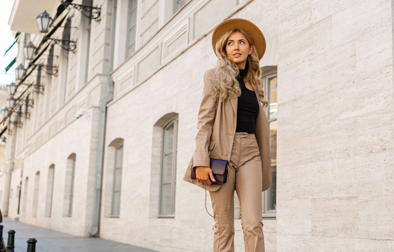 a woman walking down a street in a pale brown leather jacket and pants