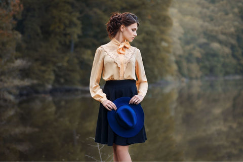 a woman wearing a vintage apricot colored blouse with a navy skirt