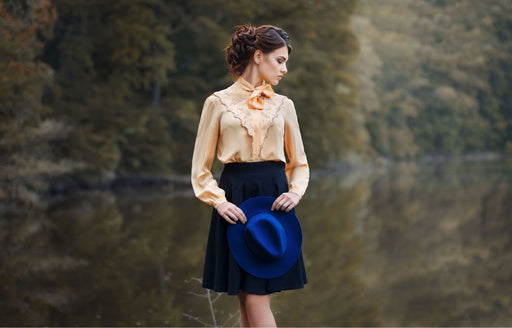 a woman wearing a vintage apricot colored blouse with a navy skirt