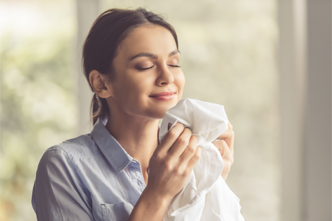 a beautiful woman smelling freshly laundered clothing