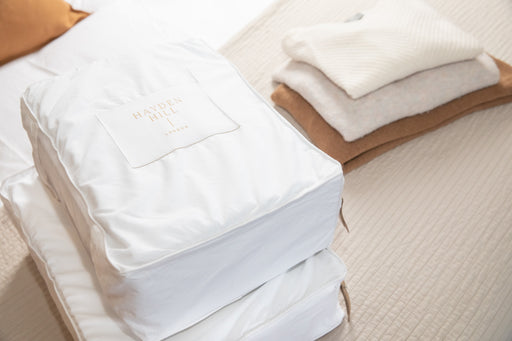 Hayden Hill 100% organic cotton sweater storage boxes next to a pile of knitwear