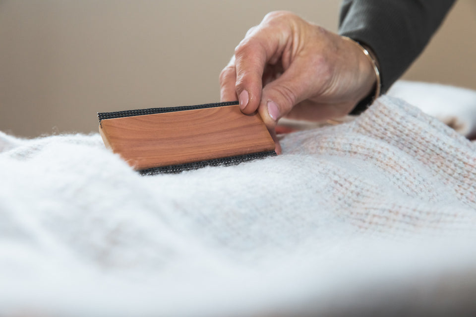 a cashmere comb being used on a soft white woolen pullover