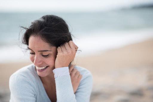 a woman on the beach wearing a pale blue sweater