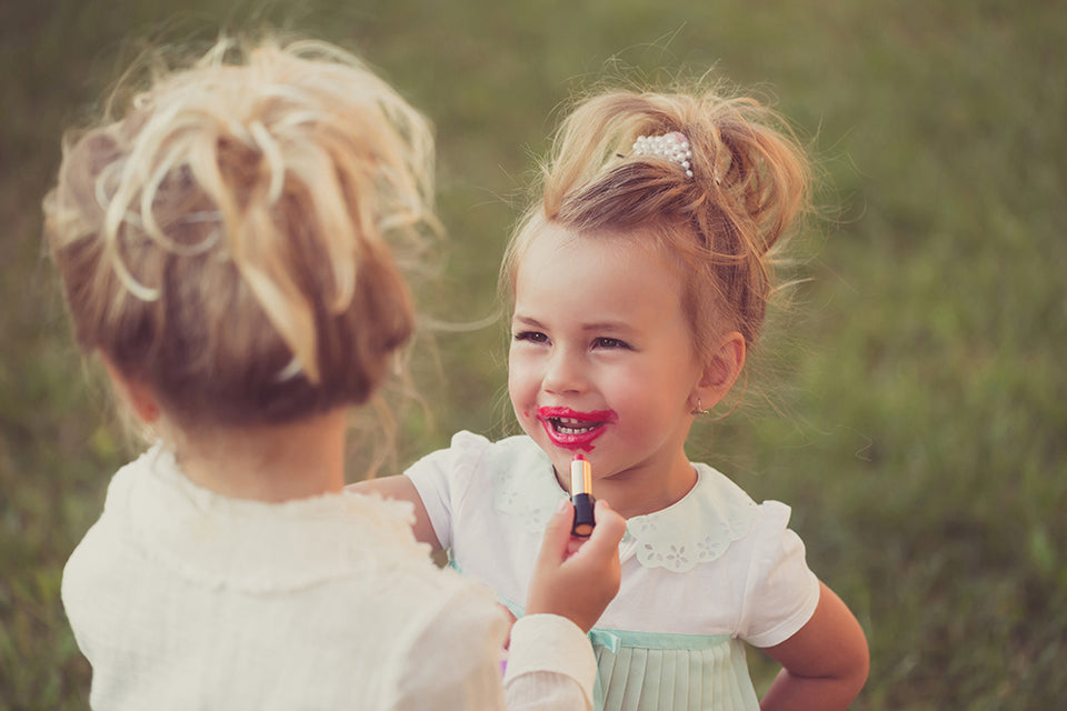 little girls playing with lipstick, one girl is covered in lipstick all over her mouth