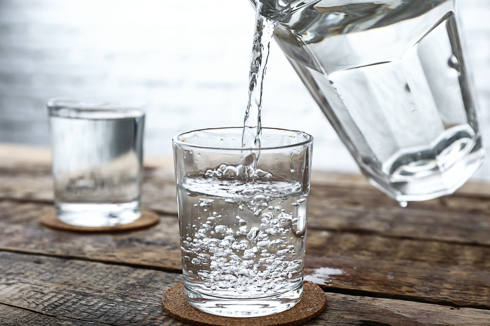 a glass of cold water being poured from a jug