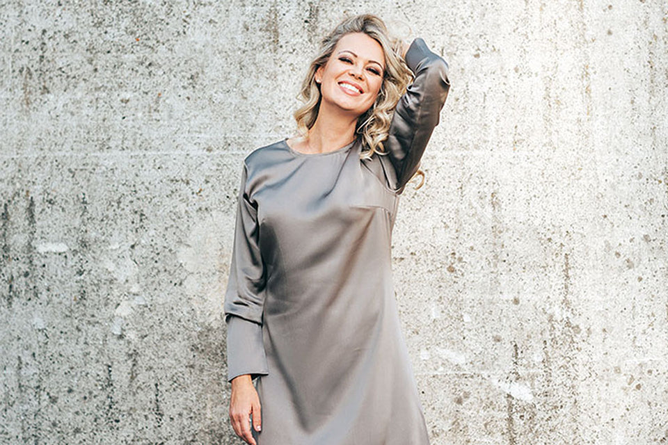 a smiling beautiful woman in a grey silk dress