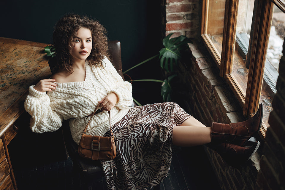 a woman wearing a chunky cream sweater, teamed with a floaty patterned skirt and boots