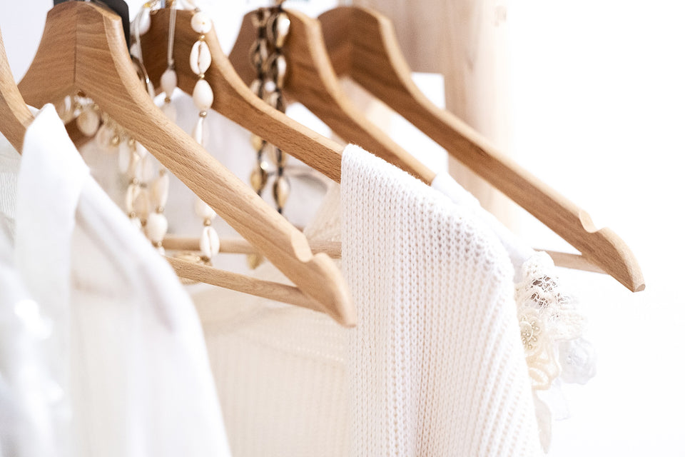 white garments and necklaces hanging on wooden hangers