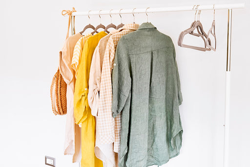 an assortment of linen clothes hanging on a rail