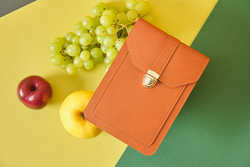 a vegan leather handbag pictured with apples and grapes