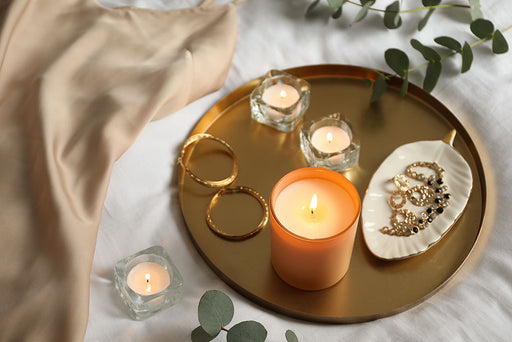 a tray with candles displaying earrings and some jewelry in a ceramic bowl