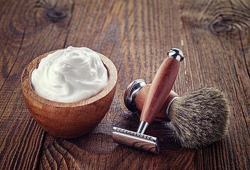 a bowl of shaving cream with a razor and bristle brush