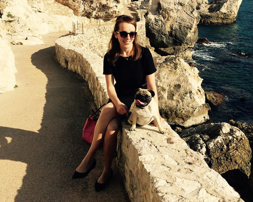 Alicia sitting by the sea in sunny Monaco with her pug dog Dorothy