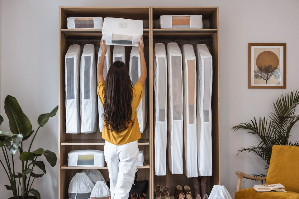 A woman storing her garments in Hayden Hill organic cotton bags using the Marie Kondo method of hanging left to right starting with darker items and ending with lighter ones.